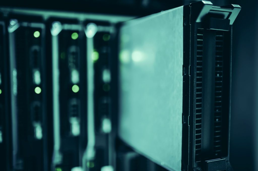 Fileiras de racks de servidores iluminados em azul dentro de um data center moderno.