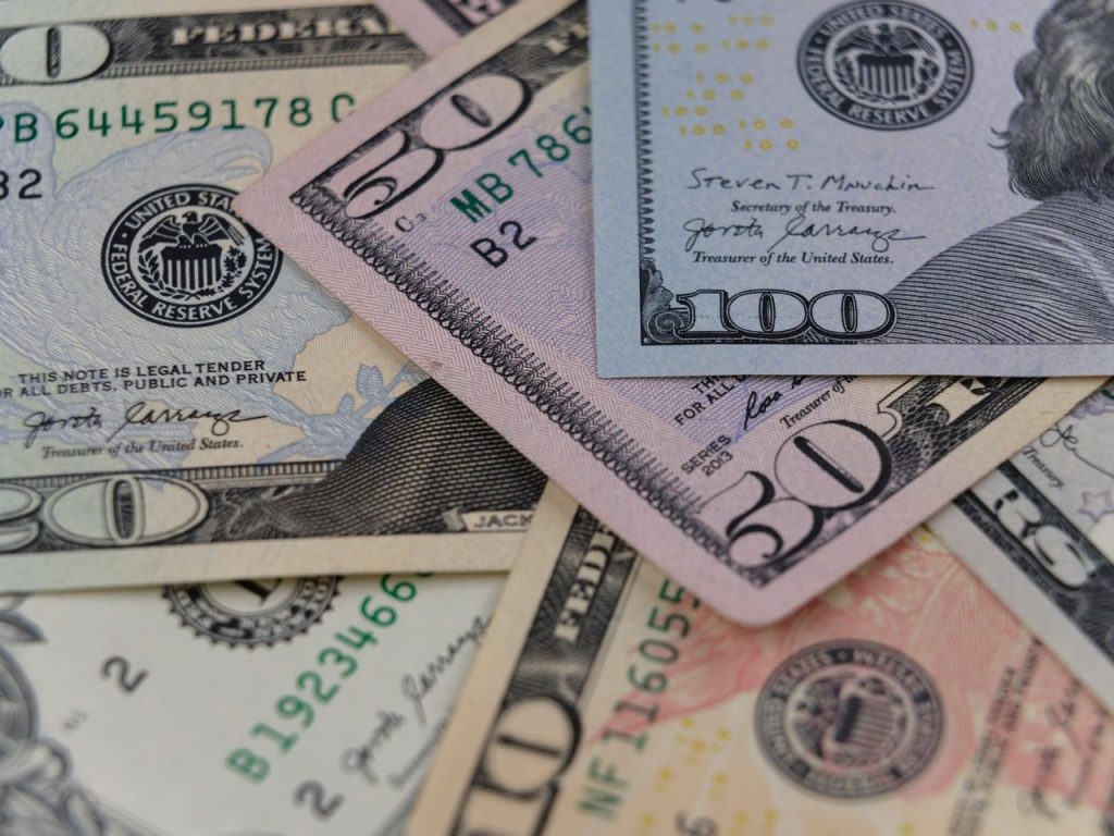 Cédulas de 50 e 100 dólares em close, representando o mercado financeiro e a circulação da moeda americana.
