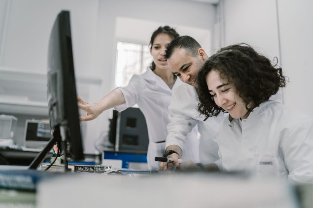 Grupo diverso de cientistas trabalha em conjunto diante de um computador em um laboratório moderno.