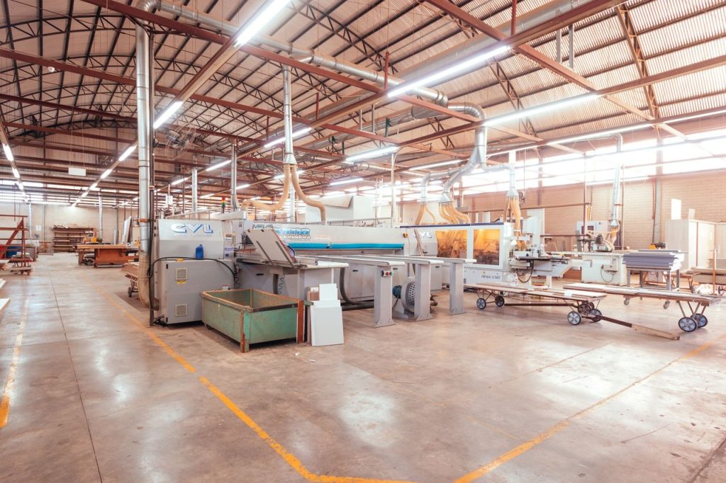 Juros altos colocam indústria de transformação no centro do alerta para 2026 Interior de uma fábrica brasileira com máquinas industriais organizadas em uma linha de produção.